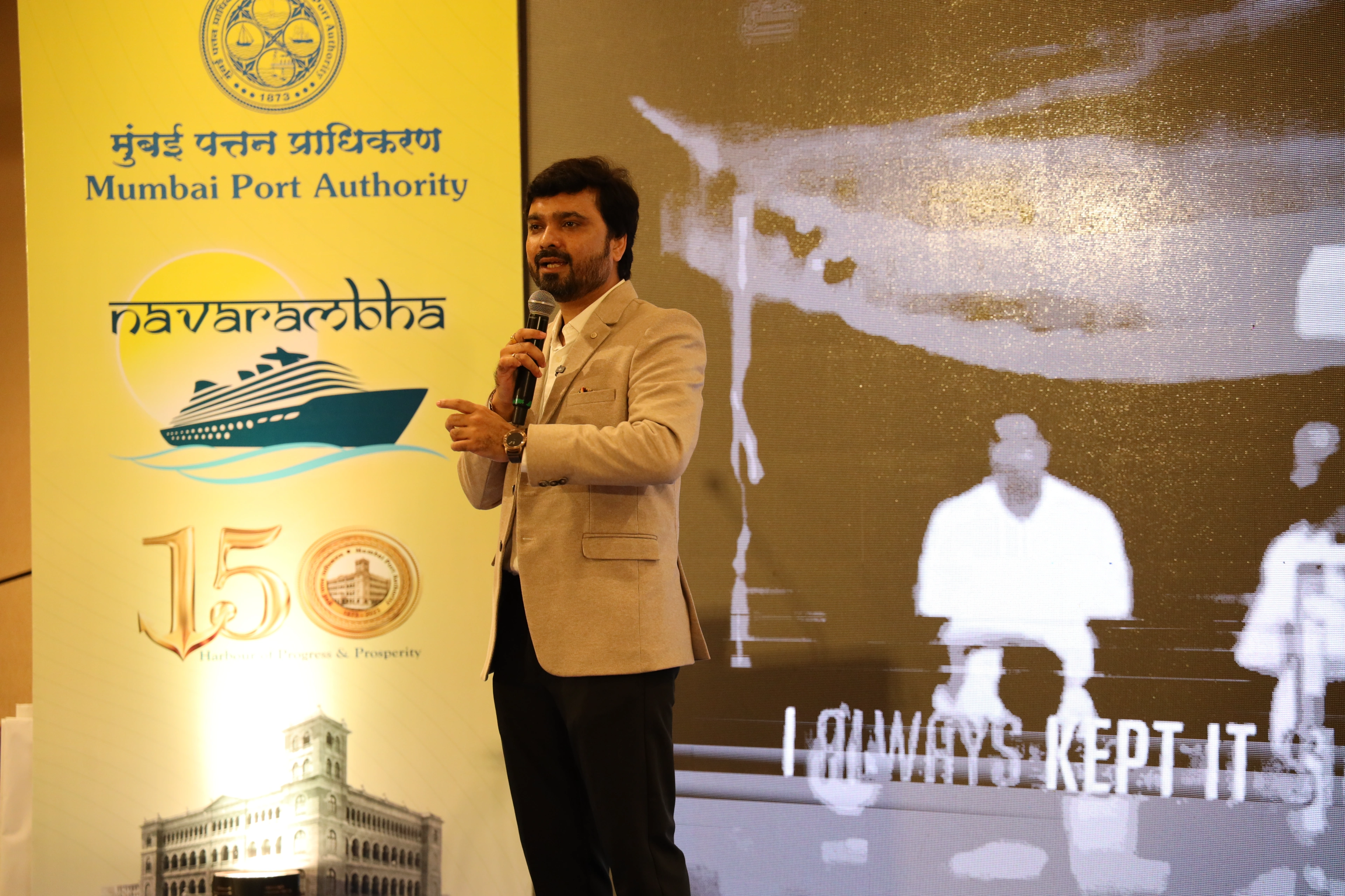 Avinash Chate speaking beside the Mumbai Port Authority Navarambha banner marking the authority’s 150 years, at the officers’ induction in Mumbai