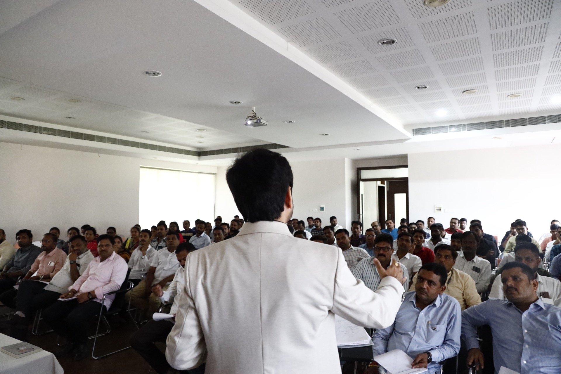 Avinash Chate seen from behind addressing a full room of seated Islampur Business Forum members during the motivation and leadership session
