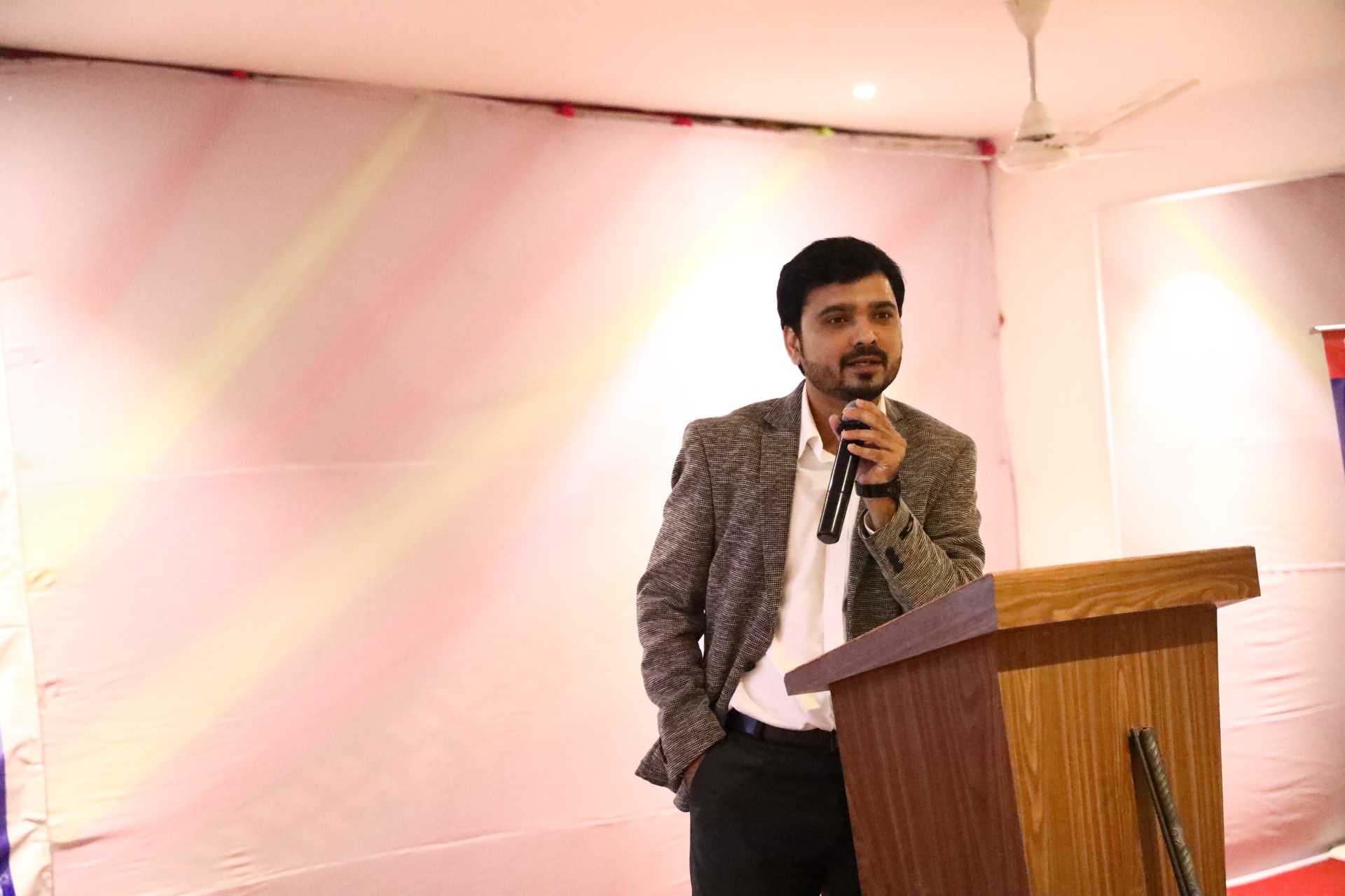 Avinash Chate speaking into a microphone from a wooden lectern at a JSW Steel session