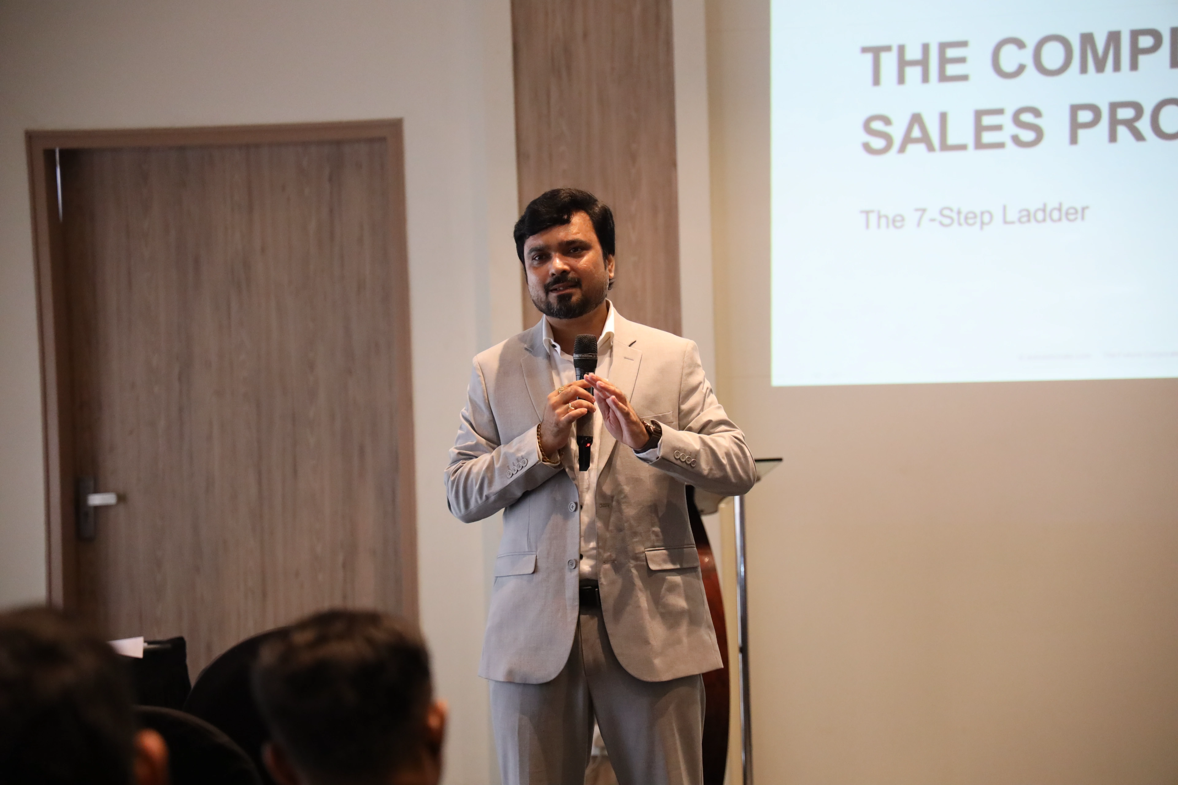 Avinash Chate with a microphone opening The Complete Sales Professional programme for Strong Wings Honda staff, a training slide on the screen behind him, Pimpri-Chinchwad